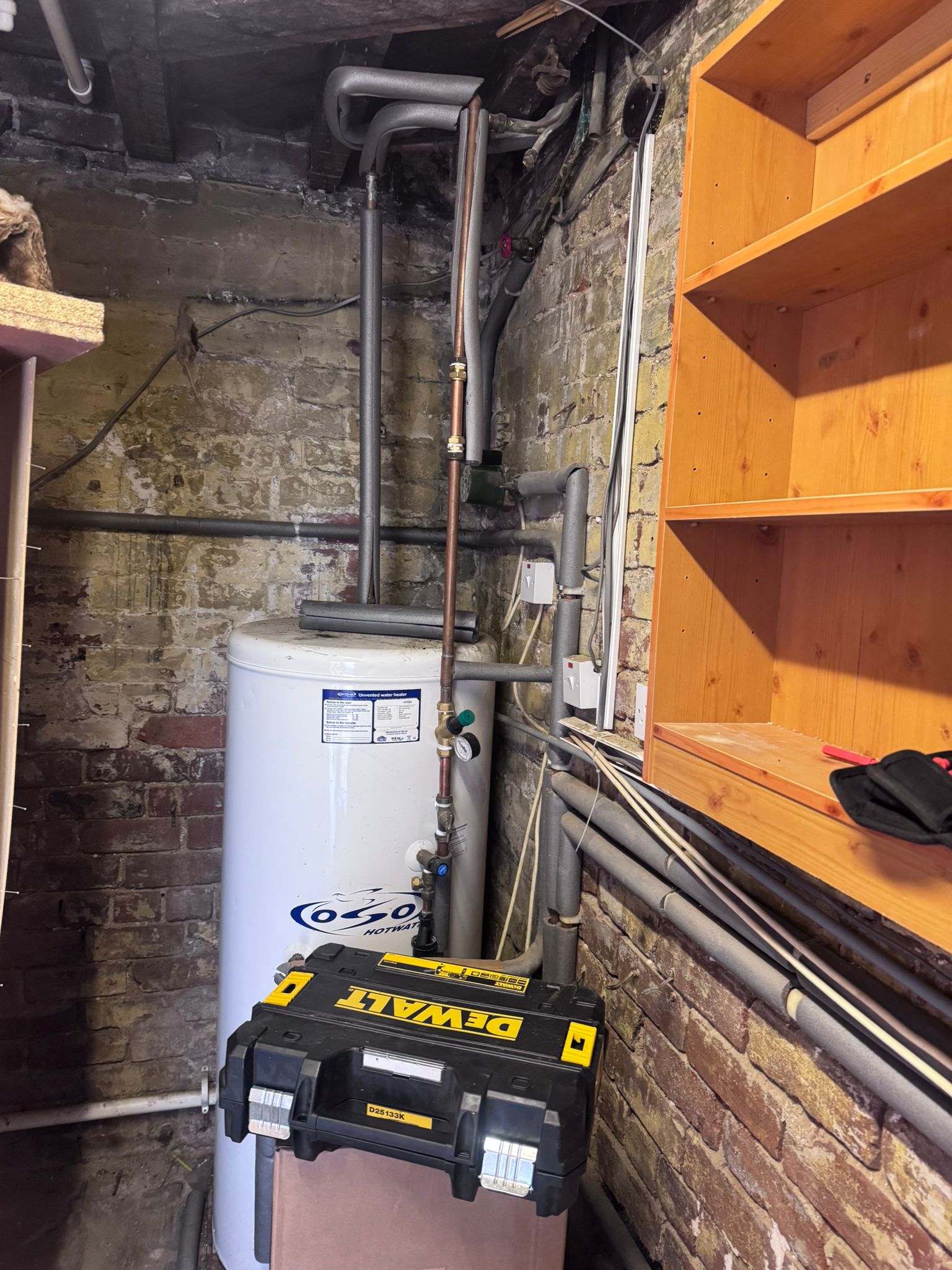 Hot water cylinder installation pipework in an airing cupboard